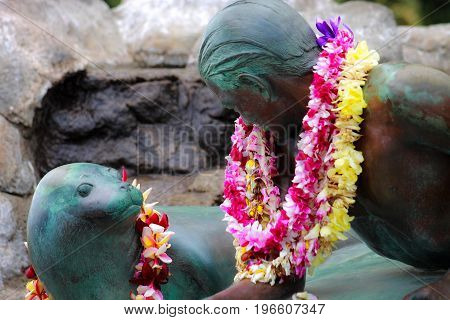 Honolulu Hawaii USA - May 28 2016: Makua and Kila bronze statue - public art sculpture shows a young surfer (Makua) sharing a moment with a monk seal (Kila).
