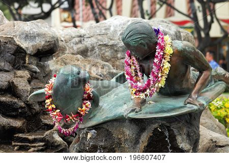 Honolulu Hawaii USA - May 28 2016: Makua and Kila bronze statue - public art sculpture shows a young surfer (Makua) sharing a moment with a monk seal (Kila).