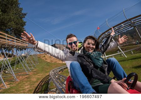 Excited young couple enjoys driving on alpine coaster