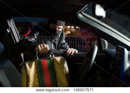 Male thief steals bag from car on parking