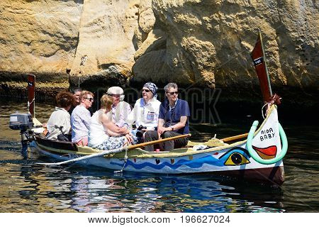 VITTORIOSA, MALTA - MARCH 31, 2017 - Passengers on board a traditional Maltese Dghajsa water taxi in an inlet alongside Fort San Angelo Vittoriosa Malta Europe, March 31, 2017.
