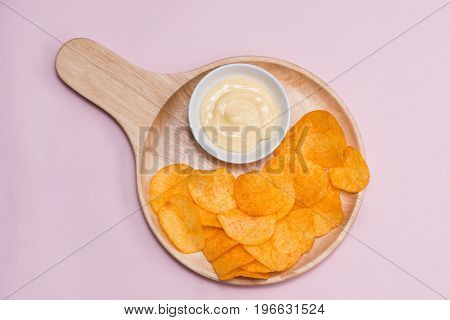 Concept of unhealthy food. Cheese and potato chips on pink background