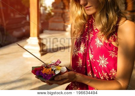 Woman holding canang sari - offering for Gods. Balinese tradition.