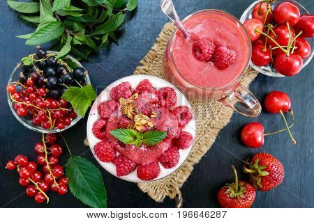 Delicious healthy dessert: yoghurt fresh berries granola raspberry sauce on a black background. The top view