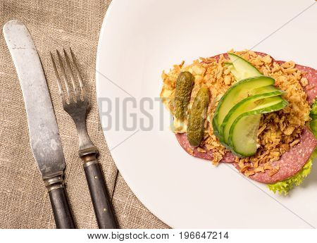 Danish specialties and national dishes high-quality open sandwich. Salami with crispy onion remoulade and cucumber served on a plate ready for eating