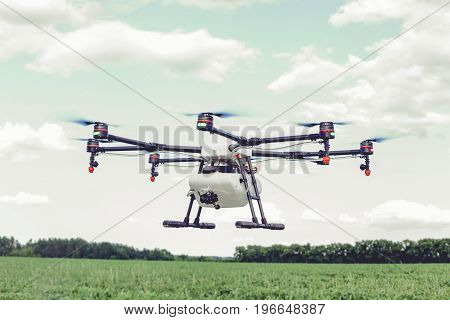 Professional agriculture drone flying and green wheat field, Hovering drone flies in blue sky and taking pictures of green hills.