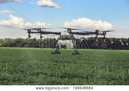Professional large drone spray water over a green field. Agriculture industry concept drone with flying green field.