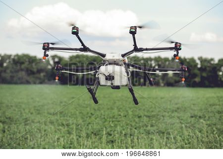 Agriculture drone spraying water or pesticides to grow over green field. Smart farming concept.