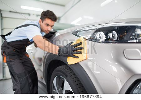 Car detailing - the man holds the microfiber in hand and polishes the car. Selective focus.