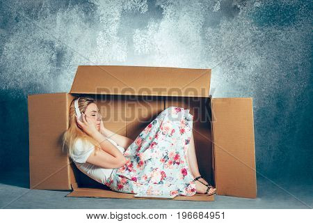 Introvert concept. woman sitting inside box and working with laptop and headphones