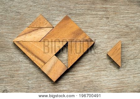 Tangram puzzle in heart shape wait to fulfill with triangle shape on wooden background