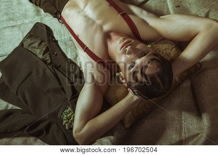 An attractive naked guy with a beautiful body lies on the floor