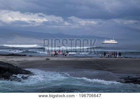 GALAPAGOS ISLANDS ECUADOR - 8 FEBRUARY 2016 - Passengers from Silversea's luxury expedition cruise ship Silver Galapagos watch and photograph wildlife on beach on Fernandina Island
