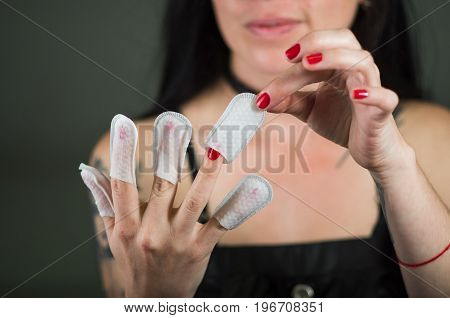Close up of young woman wearing nails protector in her nails, hand and ideal clean manicure, in a black background.