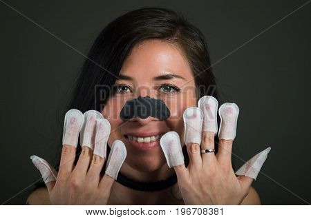 Portrait of young woman wearing nails protector in her nails, hand and ideal clean manicure, in a black background.