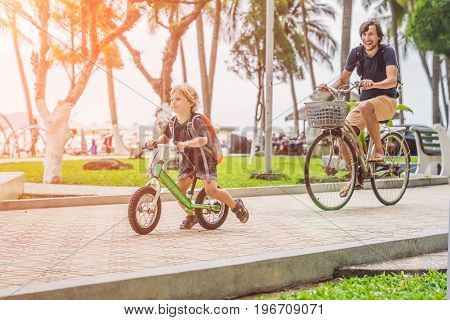 Happy Family Is Riding Bikes Outdoors And Smiling. Father On A Bike And Son On A Balancebike