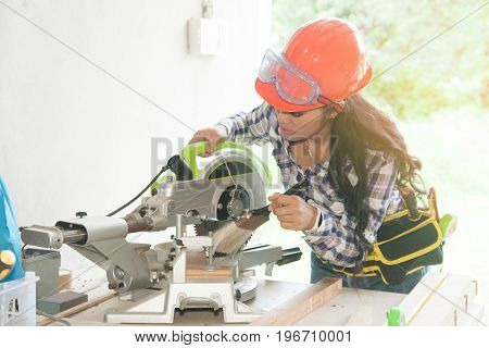 Asian pretty female carpenter using Electric Sander for wood.