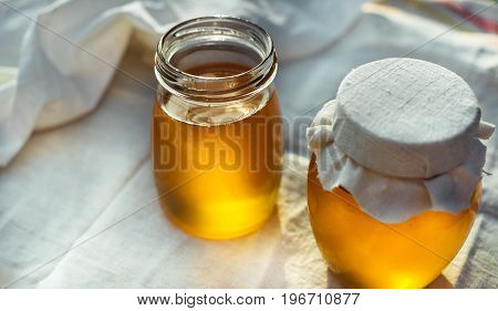 Two cans of natural honey. Honey on the fabric.