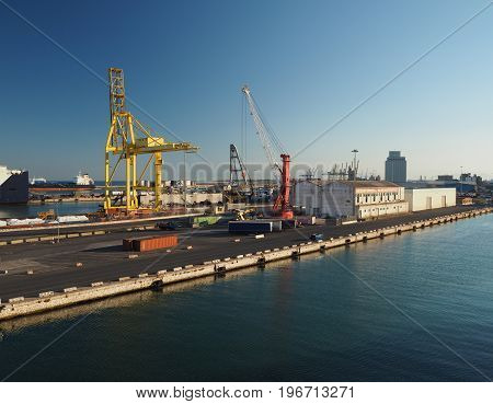 harbour in Livorno Italy with cranes and industrial buildings in golden morning light with sea and blue sky background