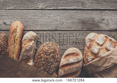 Bread border on rustic wood with copy space background. Brown and white whole grain loaves still life composition with wheat flour sprinkled around.