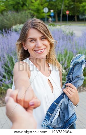 Picture of a beautiful young woman holding a human hand psoing in front on blooming lavender