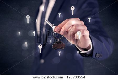 Businessman in suit holding keys with keys graphics around and dark background