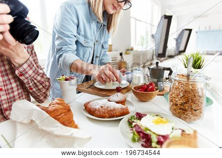 Food stylist preparing table with meals for photographing