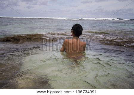 Dark-haired Girl with a naked back in a natural ocean pool