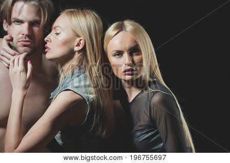 Love and romance. twins with sexy man. Relations of girls and guy. Man with muscular body with sexy women. Boyfriend and girlfriend on black