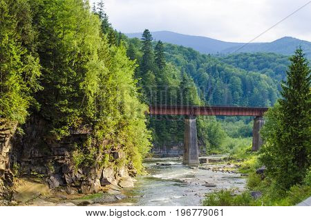 picturesque place, a mountain river with a rapid current of rocks and a bridge