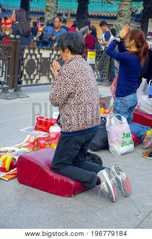 HONG KONG, CHINA - JANUARY 22, 2017: Crowd of people holding a their hands an incense sticks and praying inside of Wong Tai Sin Buddhist Temple to pray, in Hong Kong, China.