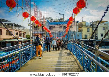 HONG KONG, CHINA - JANUARY 26, 2017: Unidentified people taking selfies over a bridge in a fishermen town in lantau, Hong Kong, China.