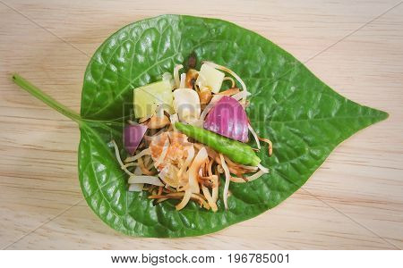 Thai Traditional Snack and Dessert Dish of Miang Kum or Sweet and Spicy Betel Leaf Wrap Filled with Coconut Peanuts Dried Shrimp Chiles and Lime.