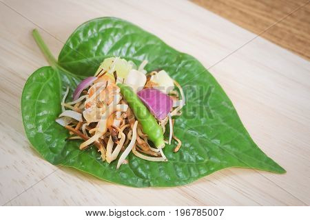 Thai Traditional Snack and Dessert Dish of Miang Kum or Sweet and Spicy Betel Leaf Wrap Filled with Coconut Peanuts Dried Shrimp Chiles and Lime.
