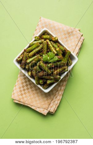 A Masala or fried vegetable dish consisting of green beans, onions, and curry spices, served in square bowl, selective focus