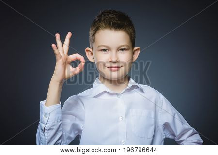 Happy boy. Closeup Portrait of handsome teenager smiling and show Ok over grey background.