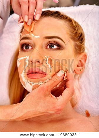 Collagen face mask. Facial skin treatment. Face of woman receiving cosmetic procedure in beauty salon close up number one isolated. Beautician removes mask. Healing clay to preserve youth.