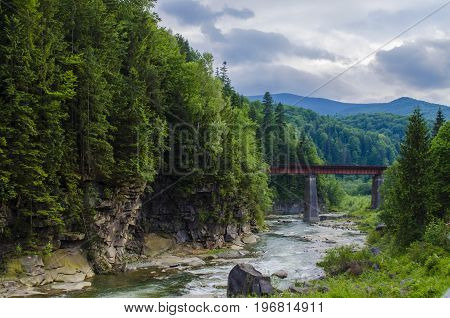 picturesque place, a mountain river with a rapid current of rocks and a bridge