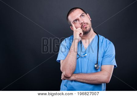 Portrait Of Doctor Wearing Scrubs With Stethoscope Thinking