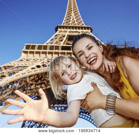 Happy Mother And Daughter Handwaving Against Eiffel Tower