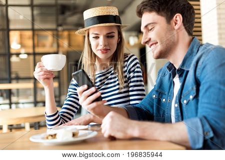 Portrait Of Young Couple Using Smartphone While Sitting Together In Cafe