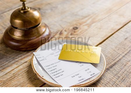 restaurant bill, credit card and waiter ring on wooden table background