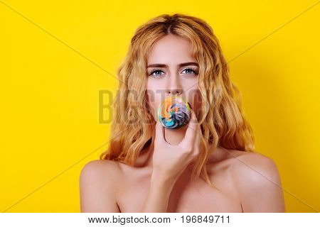 Young Blondy Female Model With Long Wavy Hair Holding Delicious Cupcake Over Yellow Background.
