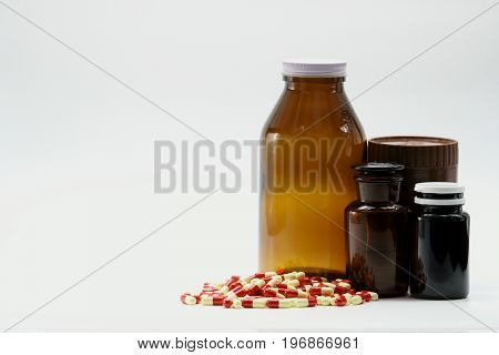 Capsule pills and amber bottles with cap on white background