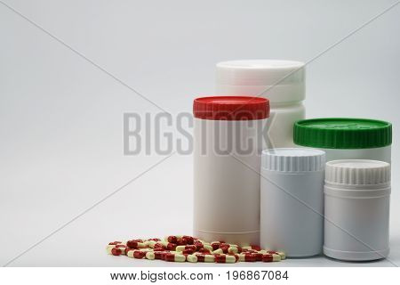 Antibiotic capsules with closed bottles on white background