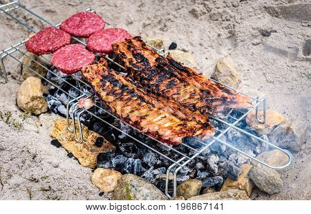Pork Ribs And Burgers On Homemade Improvised Bbq Barbecue Grill.