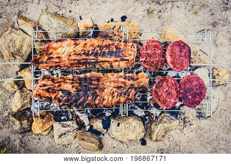 Pork Ribs And Burgers On Homemade Improvised Bbq Barbecue Grill.