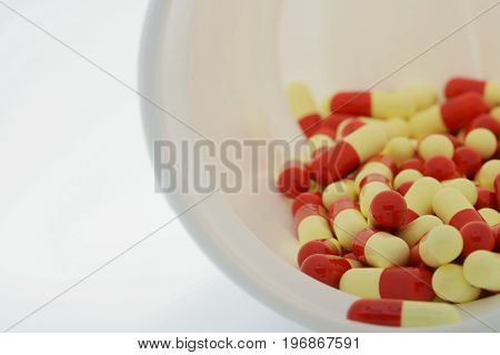 Antibiotic capsules in plastic bottle on white background