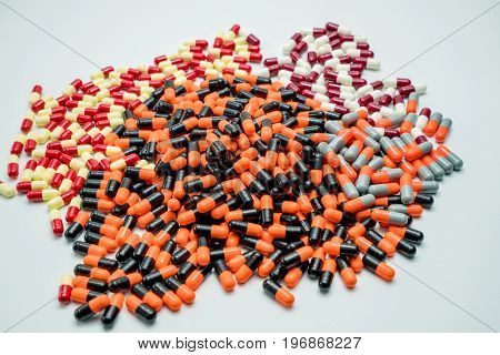 Orange black grey white red pale yellow capsule pills on white background