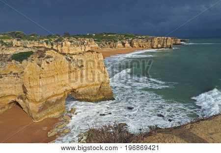 sandstone cliffs on the orange beach with azure sea and dark blue sky